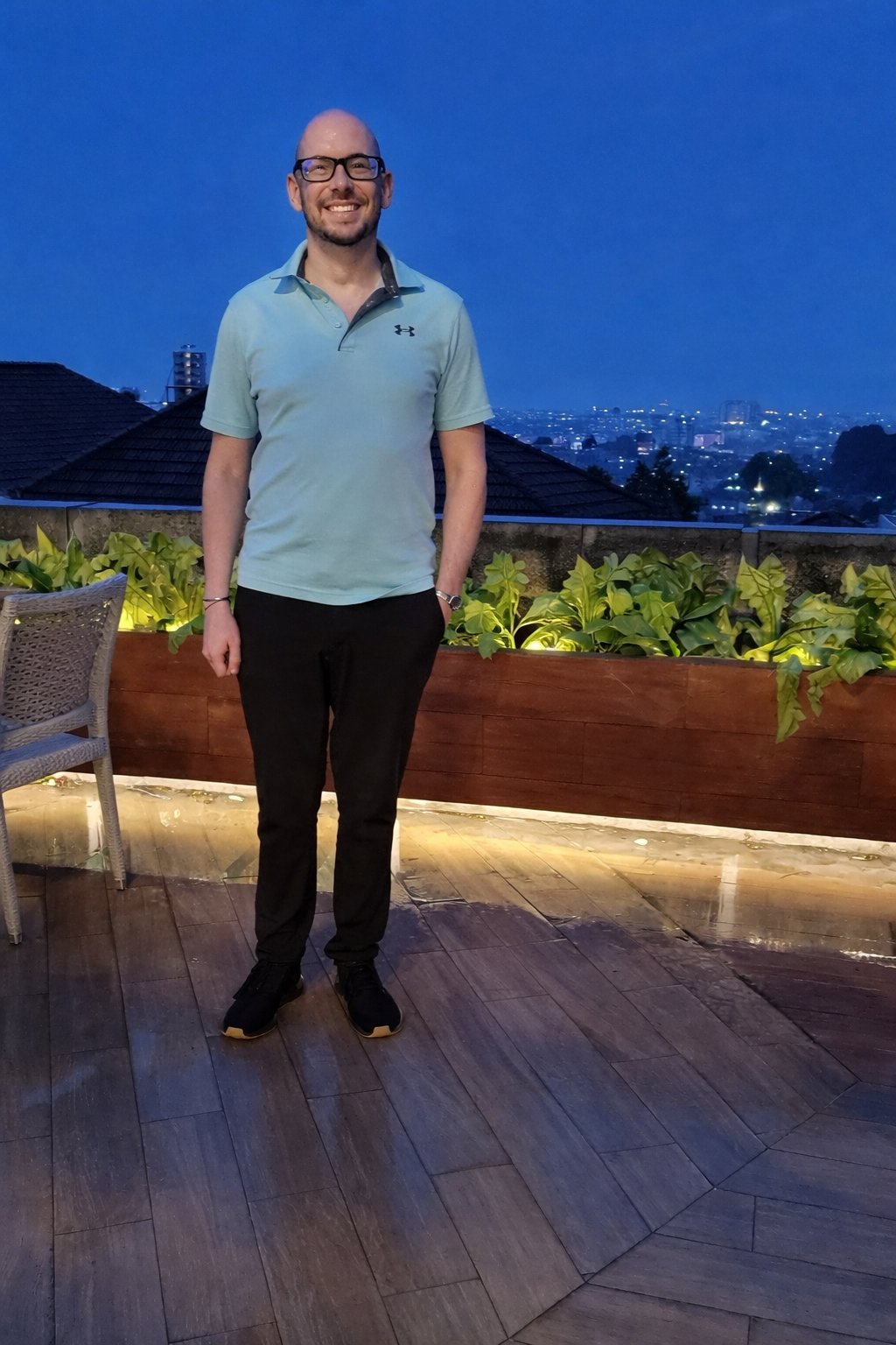 Koby on a rooftop at dusk with city skyline